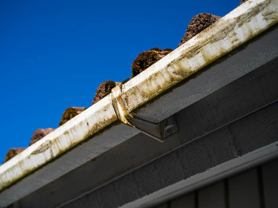Example before photo: dirty eavestrough and roof edge against a blue sky